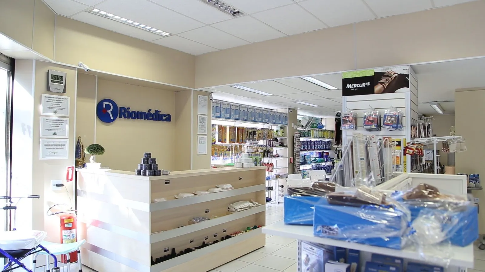 Interior da loja Riomédica: balcão de atendimento claro, logo na parede e prateleiras com produtos ao fundo